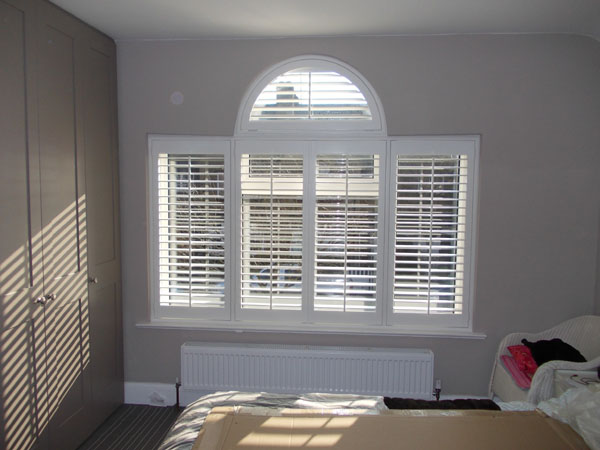 Shaped wooden plantation shutters installed in North London by Select Shutters